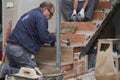 Senior bricklayer building a ceramic wood effect staircase in a home.