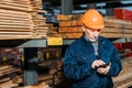 senior builder in helmet using smartphone outside