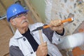 Senior builder using hammer to remove walls plaster Royalty Free Stock Photo