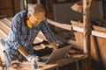 Senior builder wood worker using laptop computer at aiding design at construction work