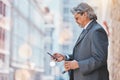 Senior, business man and cellphone in city, travel and commute, bokeh and communication outdoor. Mexican male executive Royalty Free Stock Photo