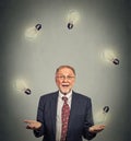 Senior business man executive in suit juggling playing with light bulbs