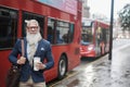 Senior business man going to work drinking coffee with london bus station in background - Focus on face