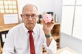 Senior business man holding piggy bank thinking attitude and sober expression looking self confident Royalty Free Stock Photo