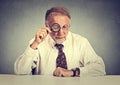 Senior business man looking through a magnifying glass sitting at office desk Royalty Free Stock Photo