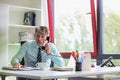 Senior business man working whilst making telephone call, he looks shocked and slamming his hand on his desk Royalty Free Stock Photo