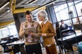 Senior business woman and her young colleague standing in office with digital tablet Royalty Free Stock Photo