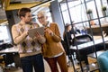 Senior business woman and her young colleague standing in office with digital tablet Royalty Free Stock Photo