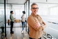 Mature man manager with a genial smile crosses his arms in satisfaction Royalty Free Stock Photo