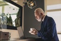 Senior businessman drinking coffee and using laptop computer Royalty Free Stock Photo