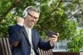 Senior businessman enjoying music with headphones outdoors in urban setting Royalty Free Stock Photo