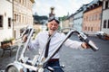 A senior businessman with motorbike in town, looking at camera. Royalty Free Stock Photo