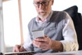 Senior businessman reading a message on his mobile phone, hard light Royalty Free Stock Photo