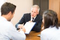 Senior businessman showing a document to sign to a couple: Document signature Royalty Free Stock Photo