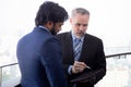 Senior businessman standing talking with partner and looking digital tablet together at office. Royalty Free Stock Photo