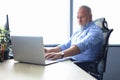 Senior businessman with a stylish short beard working on laptop computer at his office desk Royalty Free Stock Photo