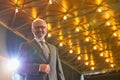 Senior businessman in suit wearing eyeglasses standing against illuminated roof