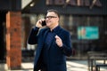 Senior businessman walking and having a conversation at phone. Portrait of mature confident smiling man wearing elegant suit Royalty Free Stock Photo