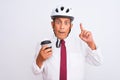 Senior businessman wearing bike helmet drinking coffee over isolated white background surprised with an idea or question pointing Royalty Free Stock Photo