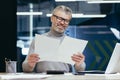 Senior businessman working in office with documents. Holds in his hands, looks at sheets of paper Royalty Free Stock Photo