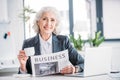 Senior businesswoman drinking coffee and reading newspaper at workplace Royalty Free Stock Photo
