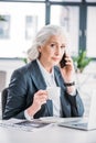 Senior businesswoman holding coffee cup and talking on smartphone Royalty Free Stock Photo