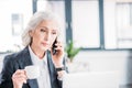 Senior businesswoman holding coffee cup and talking on smartphone Royalty Free Stock Photo