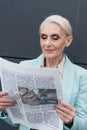 Senior businesswoman reading blurred newspaper outdoors. Royalty Free Stock Photo