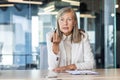 Senior businesswoman in a white blazer listening attentively during a meeting, exuding professionalism and experience in Royalty Free Stock Photo