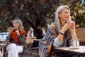 Senior cafe guests, focus on thoughtful hoary haired mature woman holding cup at table