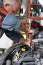 Senior car mechanic changing spark plugs on his old car in the garage.