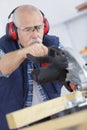 Senior carpenter cutting wooden plank with circular saw Royalty Free Stock Photo