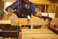 Senior carpenter in uniform gluing wooden bars with hand pressures at the carpentry