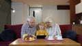 Senior Caucasian couple with cute child girl granddaughter using tablet, watching funny videos Royalty Free Stock Photo