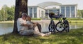 Senior caucasian couple cyclists sitting on ground under tree together in park Royalty Free Stock Photo