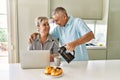 Senior caucasian couple having breakfast using laptop at the kitchen Royalty Free Stock Photo