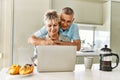 Senior caucasian couple having breakfast using laptop at the kitchen Royalty Free Stock Photo