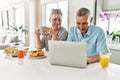 Senior caucasian couple having breakfast using laptop at the kitchen Royalty Free Stock Photo