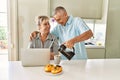 Senior caucasian couple having breakfast using laptop at the kitchen Royalty Free Stock Photo