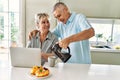 Senior caucasian couple having breakfast using laptop at the kitchen Royalty Free Stock Photo