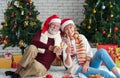 Senior Caucasian couple holding and cheers champagne flute together while sitting in front of decorated Christmas tree in cozy