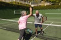 Senior caucasian couple playing tennis together on court highfiving Royalty Free Stock Photo