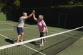 Senior caucasian couple playing tennis together on court highfiving