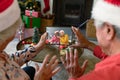 Senior caucasian couple with santa hats having christmas video call with happy diverse couple Royalty Free Stock Photo