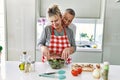 Senior caucasian couple smiling happy and hugging cooking at the kitchen Royalty Free Stock Photo