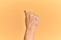 Senior caucasian hand over yellow isolated background doing protest and revolution gesture, fist expressing force and power