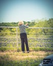 Senior Caucasian lady taking photo from mobile phone of blossom bluebonnet field over white fence