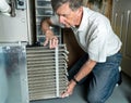 Senior man changing a dirty air filter in a HVAC Furnace Royalty Free Stock Photo