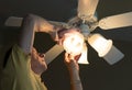 Senior caucasian man dusting lamp shade in ceiling fan and light Royalty Free Stock Photo