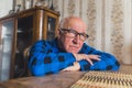 senior Caucasian man with glasses leaning on the table and looking ahead confidently medium closeup indoor senior Royalty Free Stock Photo